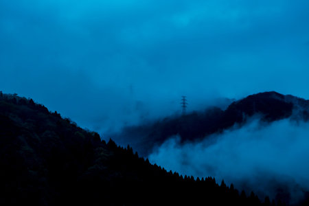 Mountains and clouds in the fog at dawn. Blue tone.