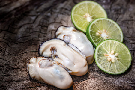 Fresh oysters with lime on wooden background. Selective focus.の写真素材