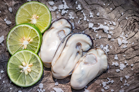 Fresh oysters with lime on wooden background. Top view. Copy space.の写真素材