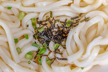 Japanese udon noodles with green onion and seaweed, close up