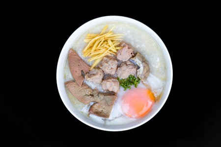 Rice porridge with pork and egg in white bowl on black background