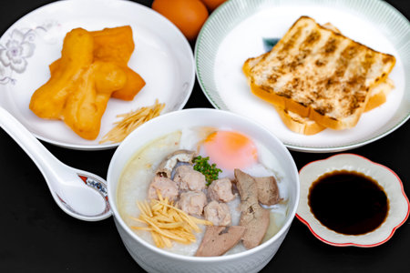 Pork porridge in white bowl and fried egg on black background