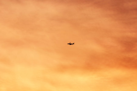 Silhouette of an airplane flying in the sky at sunset.