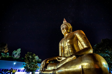 golden buddha statue at night with starry sky backgroundの写真素材