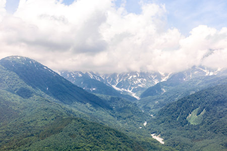 Mountain landscape with snow-capped peaks in the clouds.
