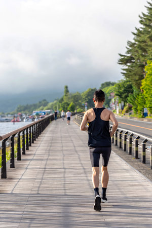 Running man jogging on wooden bridge in the morning. Healthy lifestyle concept.