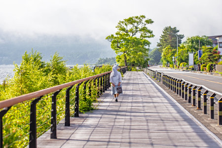 Woman walking on a wooden bridge over the lake in the morning.の写真素材