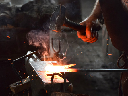 Traditional blacksmith working a piece of iron hot from the furnace.の写真素材