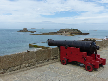 Ancient antique red cannon aimed at the sea in the city walls of Saint Malo in Brittany in France.の写真素材