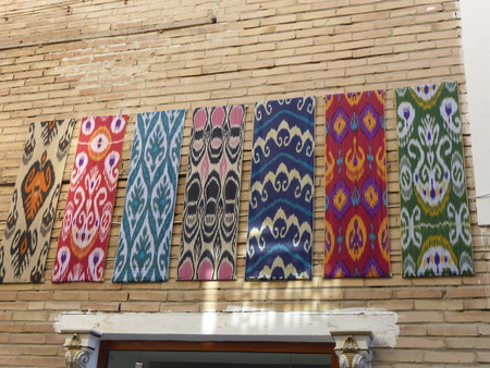 Colored fabrics with characteristic Uzbekistan patterns hanging from a wallの写真素材