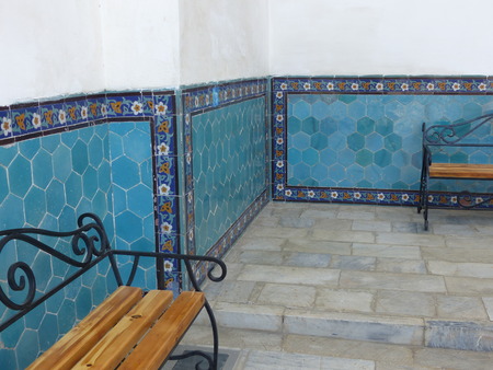 Wall of blue earthenware with wooden benches in a religious building in Uzbekistan.のeditorial素材