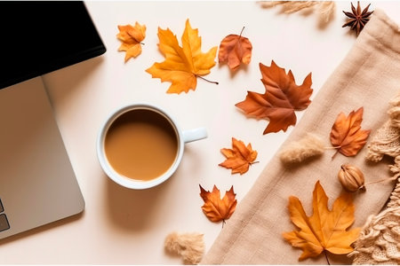 Cup of coffee, laptop and autumn leaves on beige background