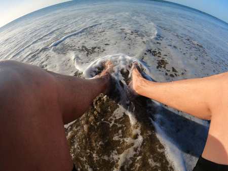 Man and woman holding hands on the seashore. See from above.の写真素材