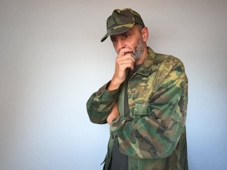 Portrait of a military man in camouflage uniform on a gray background