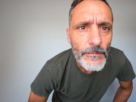 Portrait of a mature man with gray hair and beard against gray backgroundの写真素材