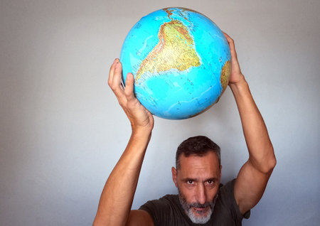 A man holds a globe in his hands and looks at the camera.の写真素材