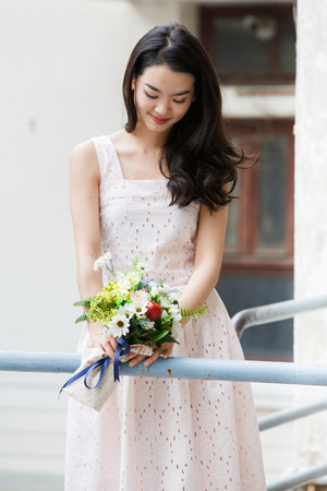 Young asian lady holding flowers in her handsの写真素材