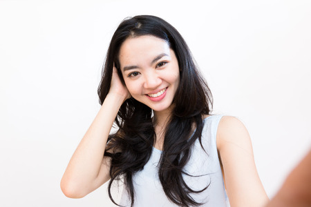 An asian woman taking self portrait isolated on whiteの写真素材