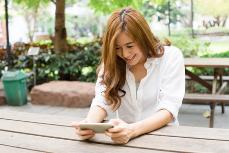 Young attractive asian female chatting on mobile phoneの写真素材