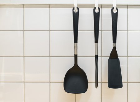 Black cooking utensils haning on the wallの写真素材