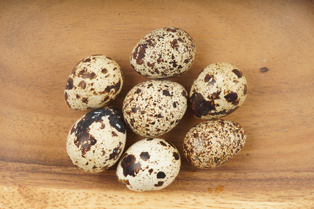 Quail egg group on brown wooden bowlの写真素材