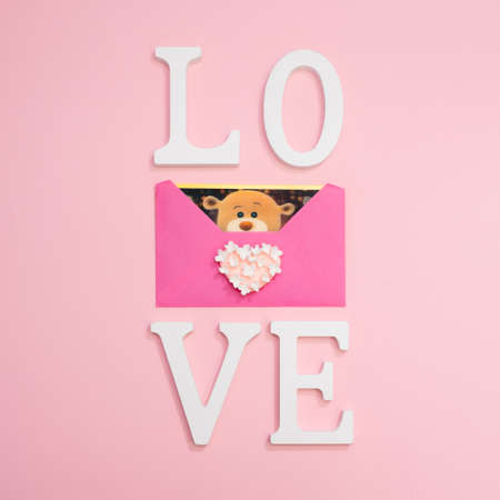 love teddy bear in a pink envelop on a pink backgroundの写真素材