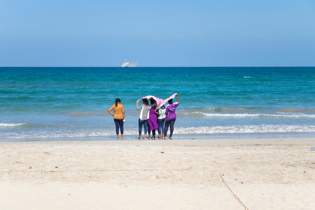 Uppuveli, Sri Lanka - March 26 2017: Colourful local girls with a sarong cloth in their hands at the...