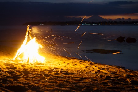 Bonfire at the beach of Gili Air with flying sparks and volcano Agung of Bali during sunset in the backgroundの写真素材