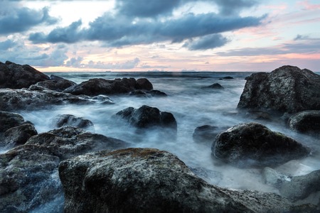 Waves in long exposure in the ocean at sunset at Koh Lanta with Stones in the sea and Phi Phi islands in the horizon, Koh Lanta, Thailand, Asiaの写真素材