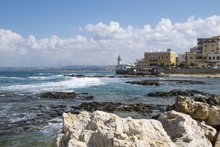 Stones and blue ocean at the coast of Tyre with lighthouse at a sunny day with blue sky in Tyre, Sour, Lebanonの写真素材