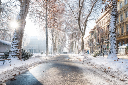 Zagreb, Croatia: January 7 2016: Footpath with decorated trees, sunbeam and walkers in Zrinjevac Park in Zagreb in winter with snow and sunny weatherのeditorial素材
