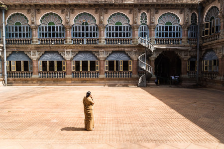 Mysore, India - December 10 2017: Yard in Mysore Palace with windows and arches in sunlight with female securityのeditorial素材
