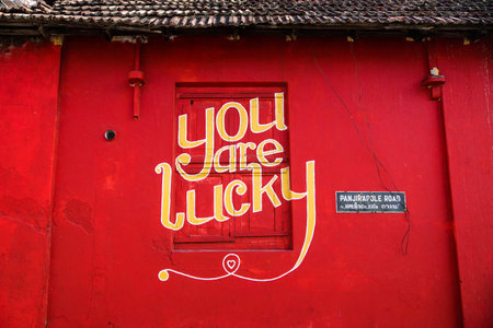 Kochi, India - 26 December 2017: 'You are lucky' yellow text on red wall and window Panjirapole Road in Kochiのeditorial素材