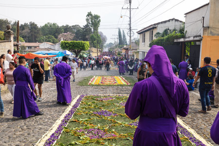 Antigua, Guatemala: March 18 2018: Purple robed man standing in front of flower carpets looking at...