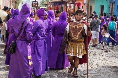 Antigua, Guatemala: March 18 2018: Man with roman soldier costume walking along purple robed men at the procession of San Bartolome de Becerra in 1a Avenidaのeditorial素材