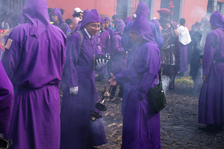 Antigua, Guatemala: March 18 2018: Two young purple robed men in incense smoke at the procession of...