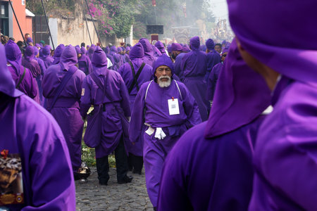 Antigua, Guatemala: March 18 2018: Older purple robed man along crowed of purple dressed men at the procession of San Bartolome de Becerra in 1a Avenidaのeditorial素材