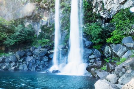 Joengbang waterfall long exposure with lens flare along the coast in Seogwipo, Jeju Island, South Koreaの写真素材