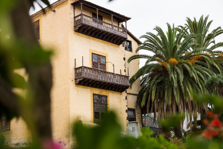 Wooden balconies on house between green palm trees in La Orotava, Tenerife, Spainの写真素材