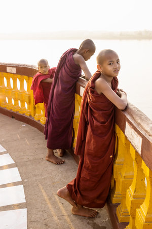 Hpa-an, Myanmar - January 9 2013: Three monks standing at the pagoda along the river enjoying the sunset, verticalのeditorial素材