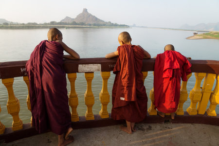 Hpa-an, Myanmar - January 9 2013: Three monks standing at the pagoda along the river with mountain enjoying the sunsetのeditorial素材