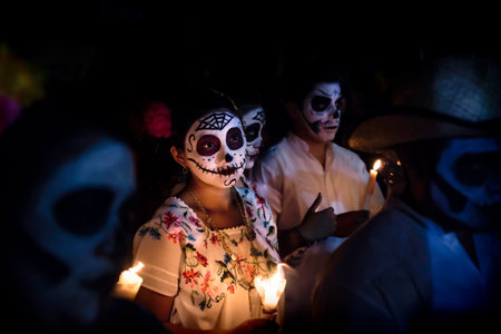 Merida, Cementerio General, Mexico - 31 October 2018: Woman with skull and spiderweb make-up and dress with traditional mexican flowers surrounded by costumed people at the parade for dia de los muertos at the Festival Des Las Animasのeditorial素材