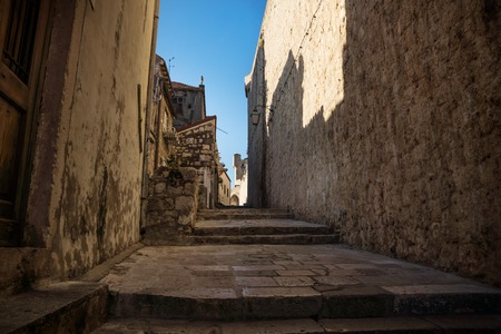 Medieval cobbled street alley with shadows on fortress wall in Dubrovnik, Croatiaの写真素材