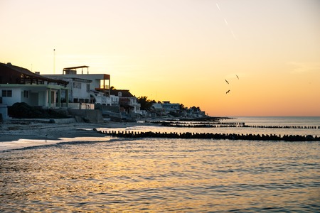 Sunset with orange sky along the coast with beach and houses of Chelem, Mexicoの写真素材