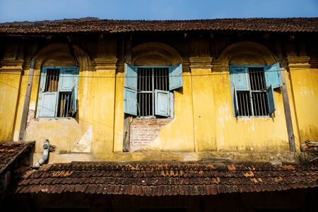 Old colonial house with three blue broken windows, Kochi, Kerala, India