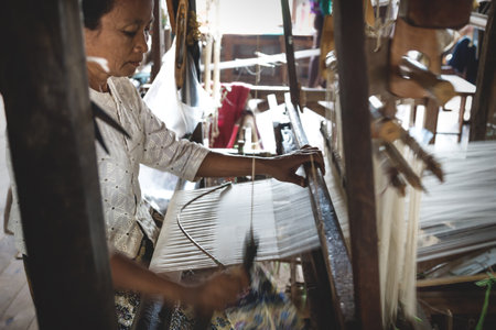 Inle Lake, Myanmar - 3 January 2013: Burmese woman weaving lotus fabric by hand on a wooden machine at Inle Lake, Myanmarのeditorial素材
