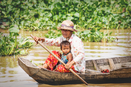 Puok, Siem Reap Province, Cambodia - 4 April 2013: Local Cambodian mother with kid rowing along Tonle Sap lake at floating villageのeditorial素材