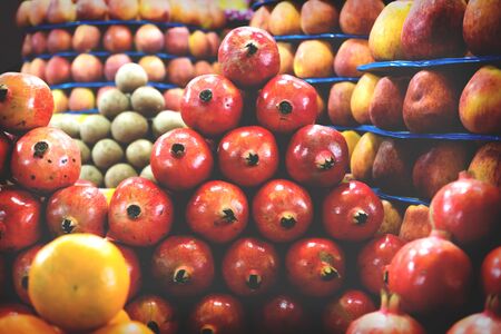 Towers of colorful fruit with pomegranates, apples and oranges at local market in Mysore, Indiaの写真素材