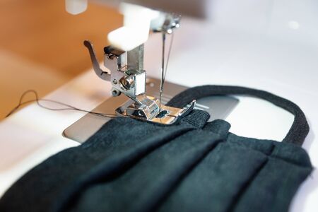 Sewing a black home made face nose mask as protection against corona virus covid-19 on a machine