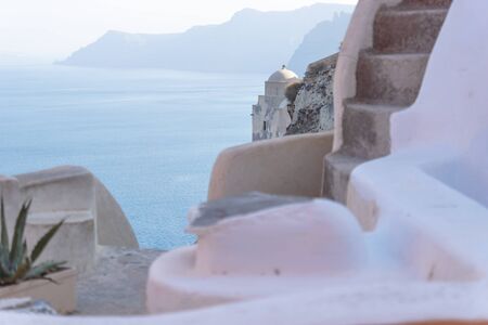 Detail of old church dome with blurred Greek building with stairs and blue seascape, Oia, Santorini, Greeceの写真素材